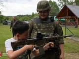 Żołnierz stoi z chłopcem trzymającym karabinek