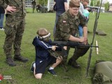 Dziecko pod nadzorem żołnierza strzela z karabinu szkoleniowego
