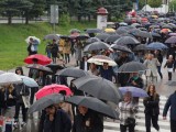 Grupa osób z parasolami idzie ulicą