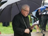 Ksiądz trzymający parasol przemawia