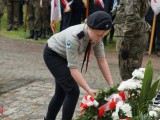 Harcerka układa kwiaty przed pomnikiem