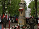 Żołnierze i kwiaty przy pomniku, w tle grupa osób