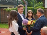 Uczniowie wręczają kwiaty dyrektorowi szkoły