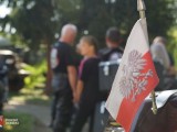 Flaga biało-czerwona z godłem, w tle grupa osób