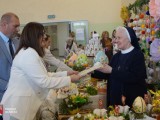 Wręczenie dyplomu siostrze zakonnej za udział w wydarzeniu – w tle ozdobne jaja i dekoracje
